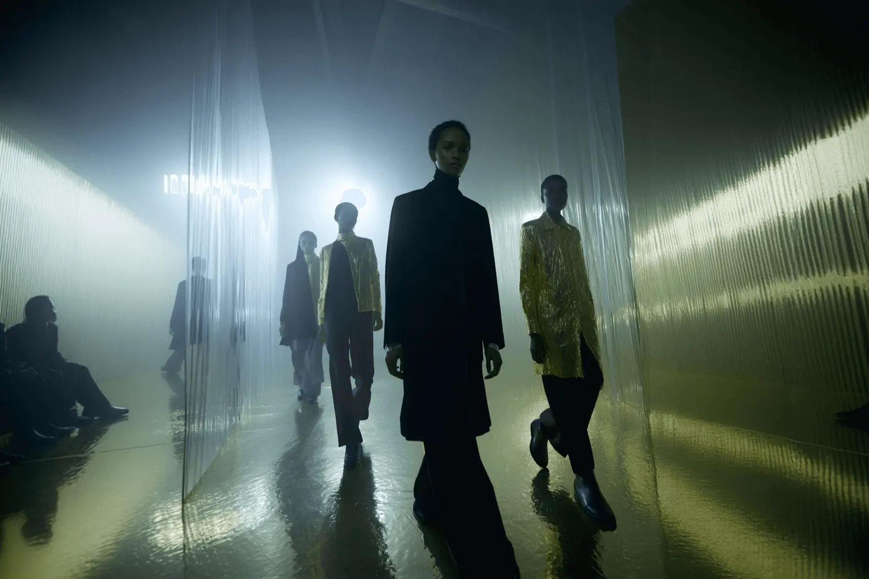 Models walking a runway down a misty, lit corridor